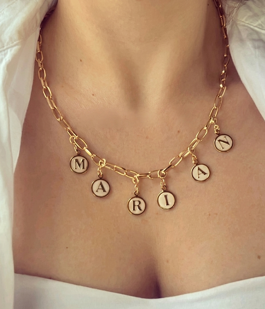 Gold necklace with circular pendants on a person wearing a white garment.
